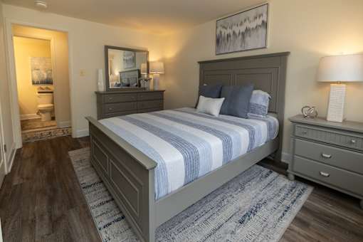 A bedroom with a large bed and a painting on the wall.