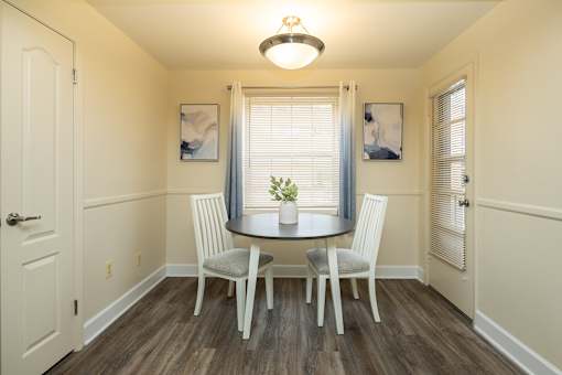 A dining room with a table and chairs.