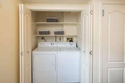 Full-sized washer and dryer with shelving with baskets behind closet doors at Ivy Hall Apartments*, Maryland, 21204