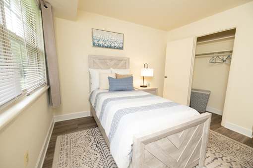 Second bedroom with bed, nightstand with mirror, and closet at Village of Pine Run Apartments & Townhomes*, Maryland, 21244