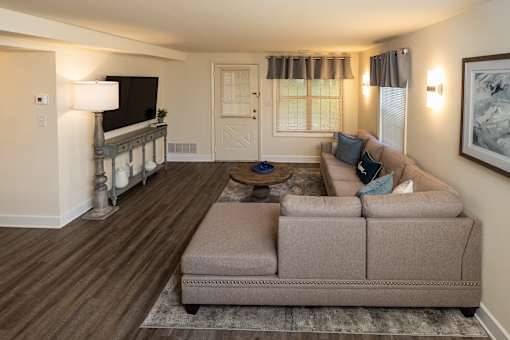 A living room with a couch, a coffee table, and a television at Spring Hill Apartments & Townhomes, Baltimore, MD 21234. .