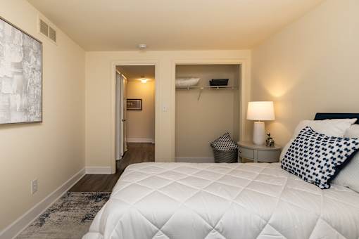 A bedroom with a large bed and a painting on the wall. Spring Hill Apartments & Townhomes, Baltimore, MD 21234