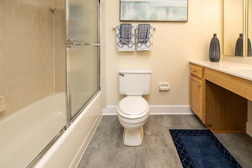 A white toilet sits in a bathroom next to a bathtub.