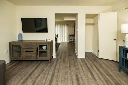 A living room with a tv on the wall and a cabinet with glass doors.