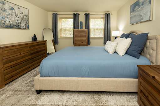 A bedroom with a blue bedspread and a wooden headboard.