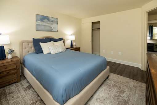 A bedroom with a large bed and a painting on the wall.