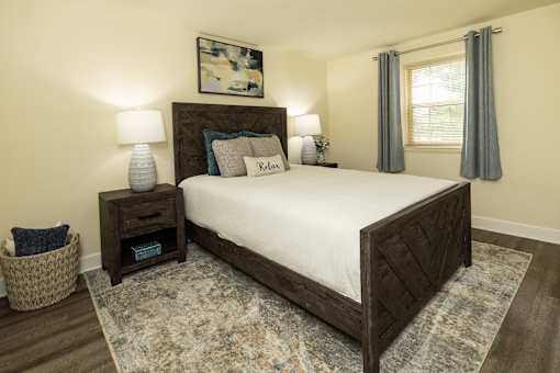 A bedroom with a large bed and a painting on the wall.