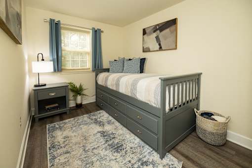 A bedroom with a bed, nightstand, and window.