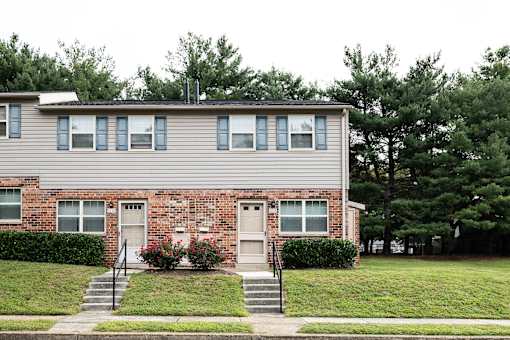 A two-story house with a brick facade and a grey siding.