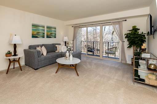 A living room with a grey couch, a white coffee table, and a painting on the wall.