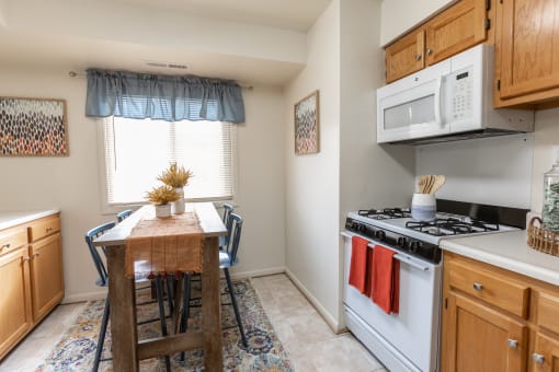 a kitchen with a table and chairs in front of a window at Lawyers Hill Apartments, Elkridge, 21075