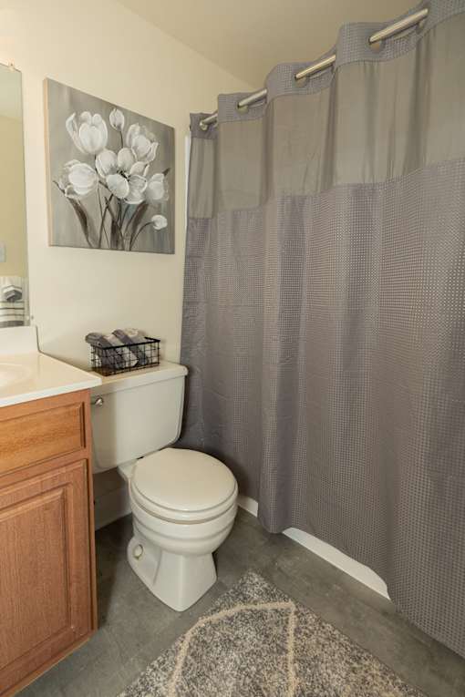 A white toilet in a bathroom with a grey shower curtain