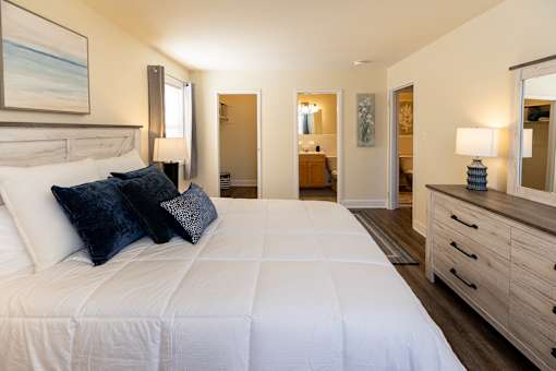 A bedroom with a large bed, a dresser, and a mirror.