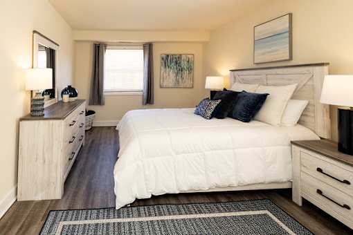 A bedroom with a large bed, a dresser, and a painting on the wall.