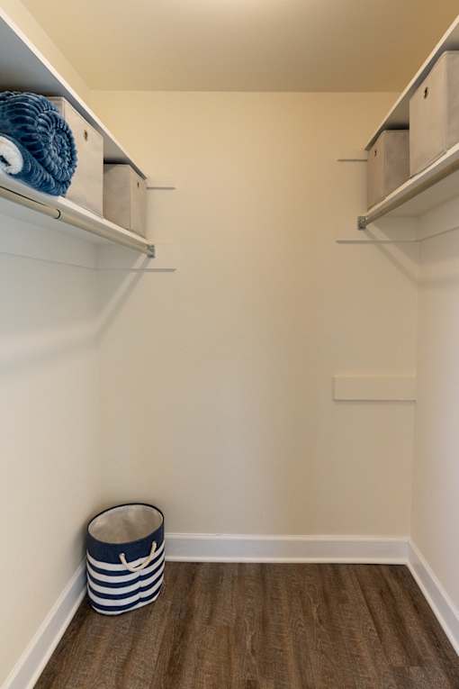 A walk in closet with a striped basket on the floor.