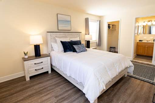 A bedroom with a large bed, a nightstand with a lamp, and an area rug.