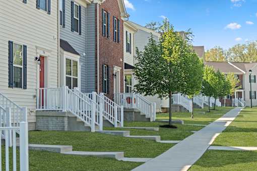 A row of houses with white railings and steps leading to the doors.