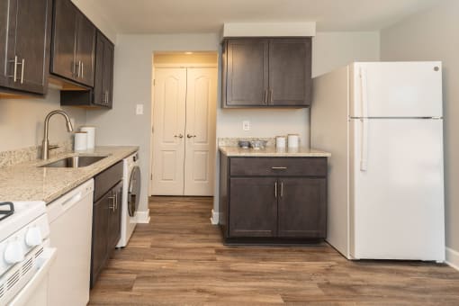 A kitchen with white appliances and brown cabinets at Fairbrook Park, Maryland, 21244