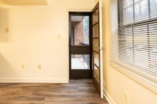 Open door leading to a balcony with a brick building in the background at Ivy Hall Apartments*, Towson, MD