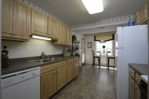 a kitchen with white appliances and wooden cabinets at Ivy Hall Apartments*, Towson