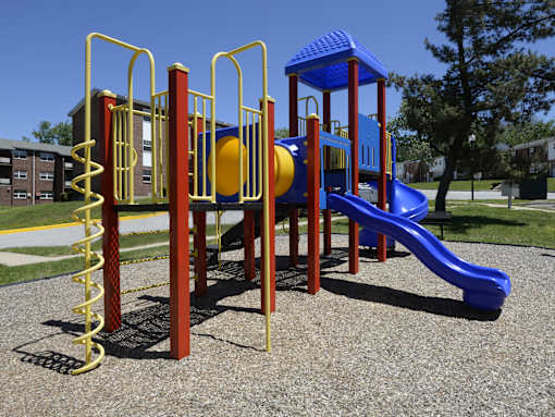 A playground with a blue slide and yellow and red play structures at Colony Hill Apartments & Townhomes, Baltimore, MD
