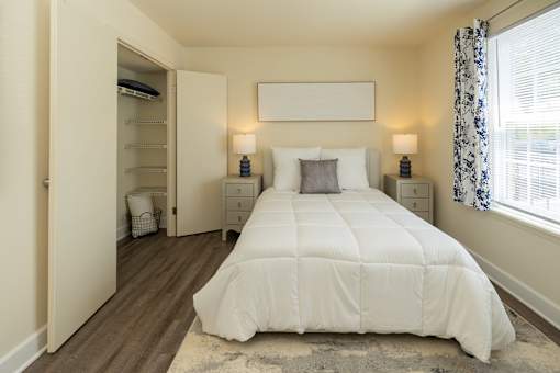 A bedroom with a large bed and a window with curtains at The Brittany Apartments, Pikesville, MD, 21208