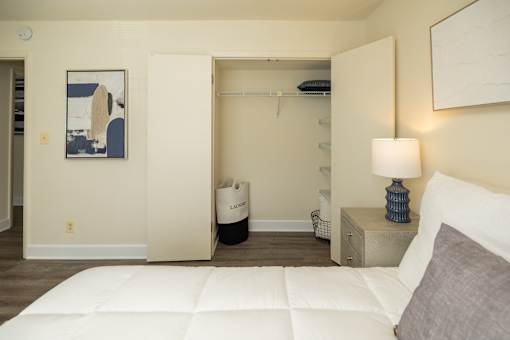 A bedroom with a white bed and a painting on the wall at The Brittany Apartments, Pikesville, Maryland