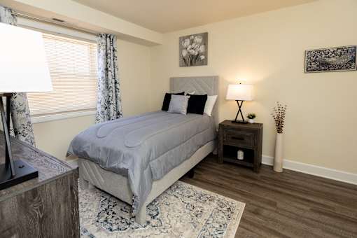 A second bedroom with a bed, nightstand, and lamp.