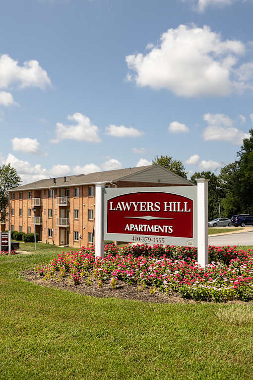 A sign for Lawyers Hill Apartments in front of a building.