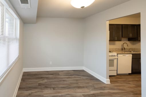 A bedroom with a window and a kitchen at McDonogh Village Apartments & Townhomes, Randallstown, MD