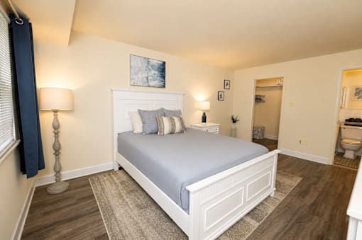 Primary bedroom with furniture looking into walk-in closet and en-suite bathroom at Village of Pine Run Apartments & Townhomes*, Maryland, 21244