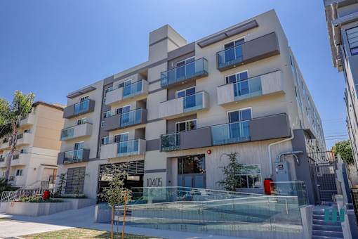 a white apartment building with balconies and a glass staircase
