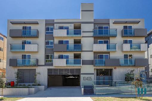 a white apartment building with blue balconies and a garage
