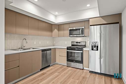 A modern kitchen with wooden floors and stainless steel appliances.