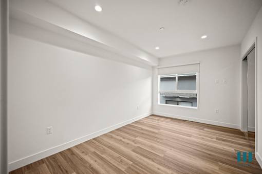 A spacious room with wooden flooring and a window.