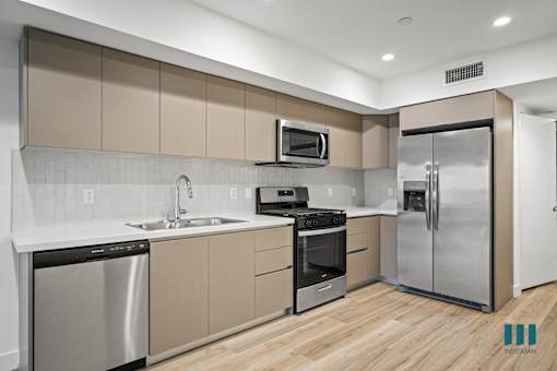 A modern kitchen with stainless steel appliances and wooden floors.