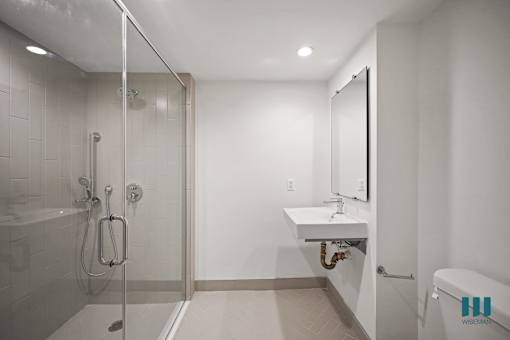 A bathroom with a white sink and a glass shower stall.