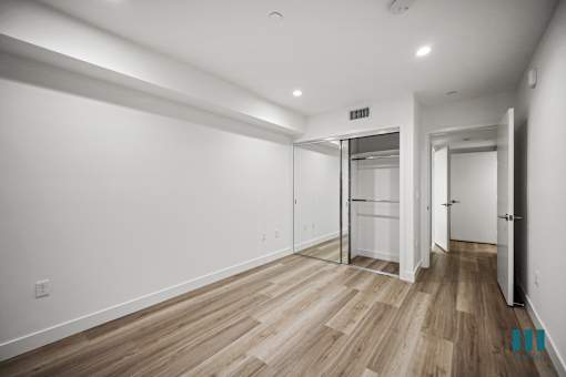 A room with white walls and wood flooring with a door on the right.