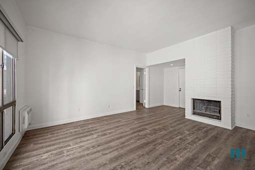A spacious living room with a fireplace and wood flooring.