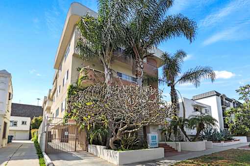 an apartment building with palm trees in front of it