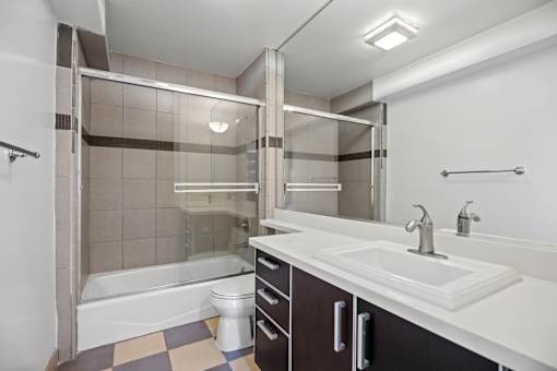 Bathroom with Bathtub with Glass Doors and Cabinet Storage