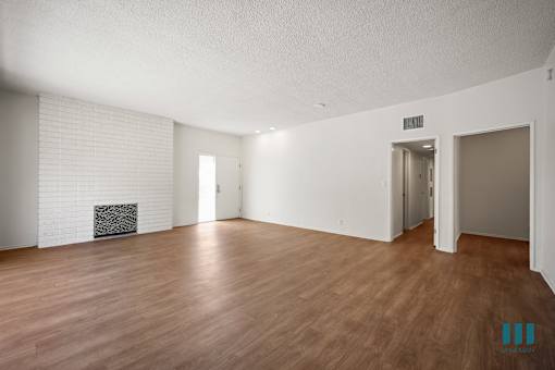 an empty living room with wood flooring and a fireplace