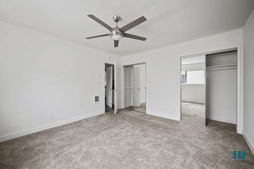 Bedroom with Two-Mirrored Closets, Ceiling Fan, and Carpet