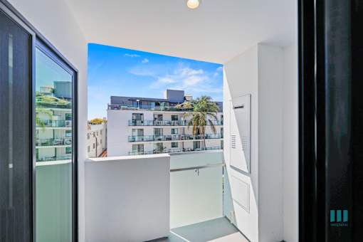 A white room with a large screen on the wall showing a building with palm trees.