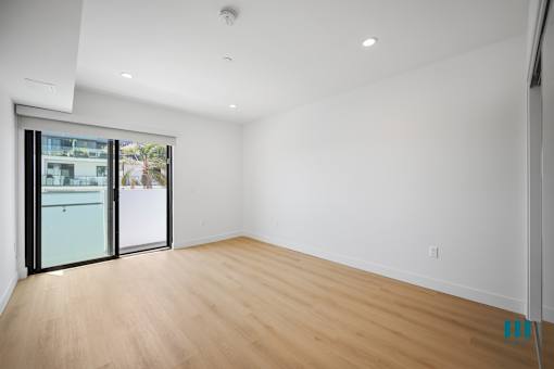 A room with a sliding glass door leading to a balcony.