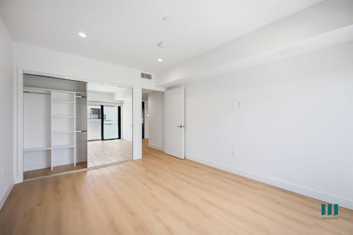 A spacious room with wooden floors and white walls.