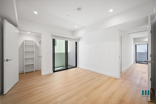 A spacious room with wooden floors and white walls.