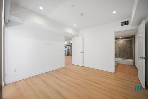 A spacious room with wooden floors and white walls.