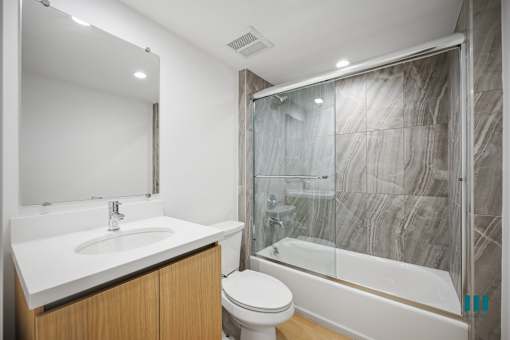A modern bathroom with a white sink, toilet, and bathtub.
