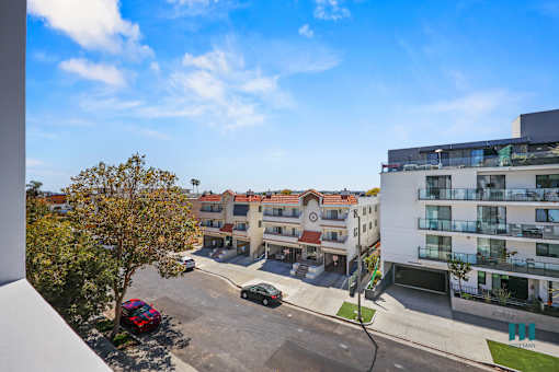 A view of a residential area with apartment buildings and cars parked on the street.